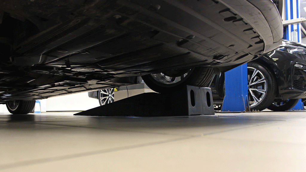 Technicien automobile inspectant véhicule occasion sur pont élévateur